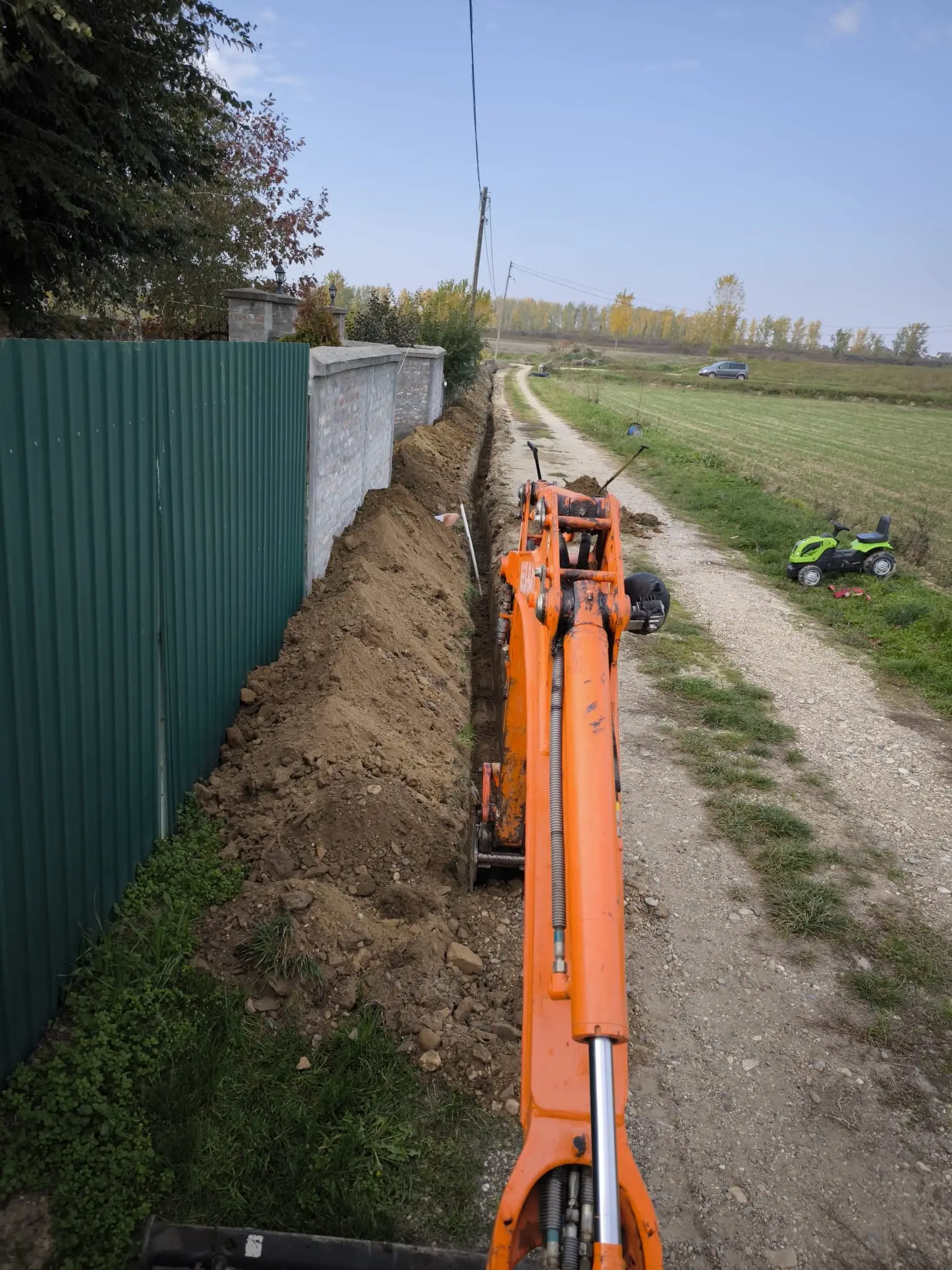 Dugačak iskopan kanal za vodovod uz zidanu ogradu pored seoskog puta