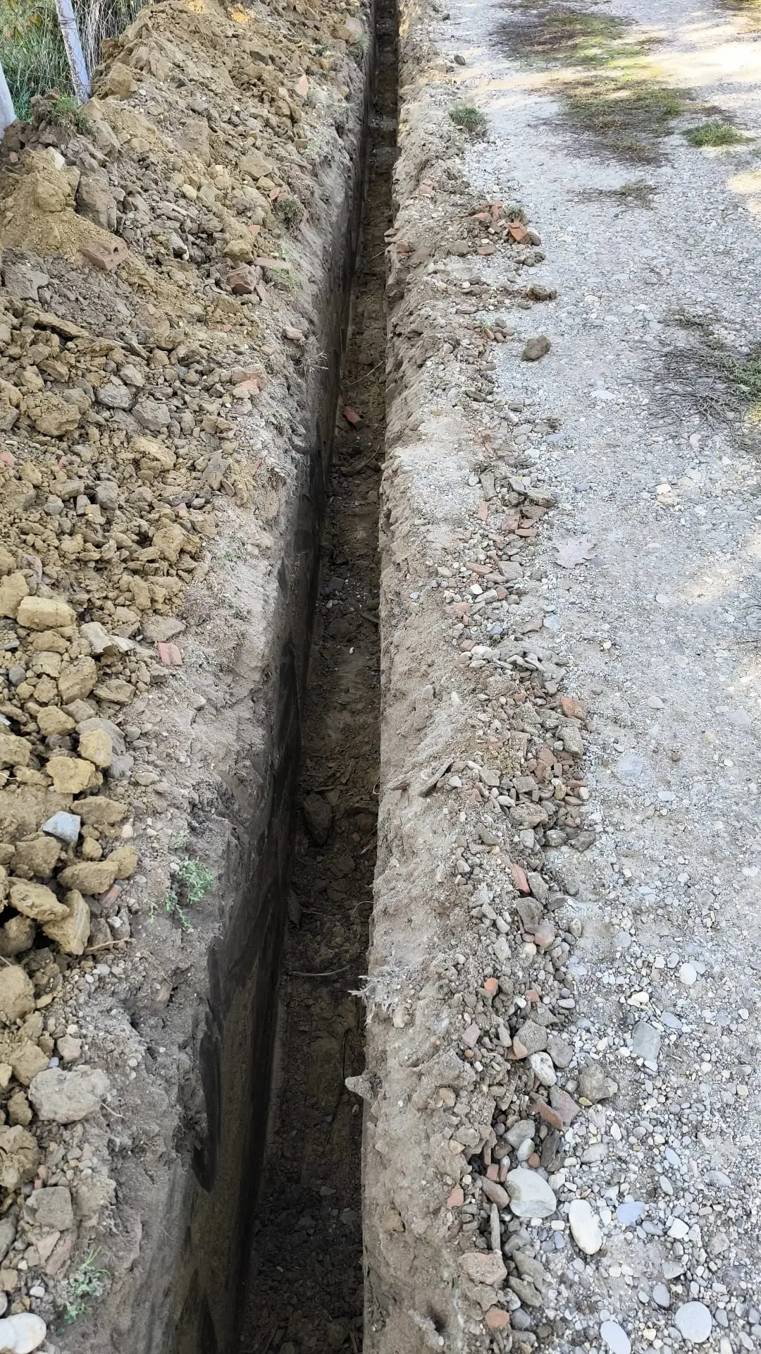 Uzak i dubok kanal precizno iskopan mini bagerom pored puta